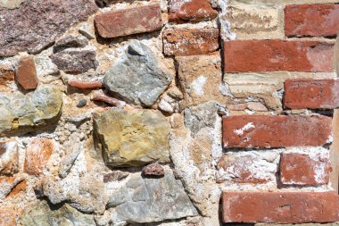 Neredeyse duvar yüzeyini yok ediyordu. Granit taşlar ve tuğlalardan yapılmış eski bir duvar. Doğal malzemeler.