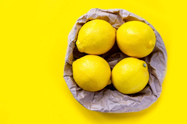 Geri dönüşüm poşetinde bir grup taze limon. Çevre ambalajı. Sarı arka planda dört olgun limon. — Stok fotoğraf