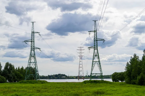High voltage transmission power tower, electricity pylon stand on the river bank and one on piles on the water. Nature landscape. Daugava river, Latvia