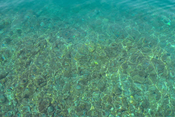 Texture of transparent shallow water surface. Rippling water background. Aerial view rocky bottom of Adriatic sea in sunny day. Journey Croatia.