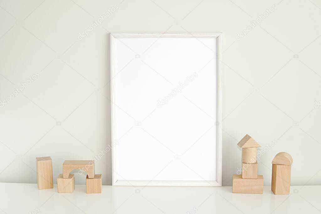 White frame mockup for nursery or kids room, blank photo frame and wooden cubes.