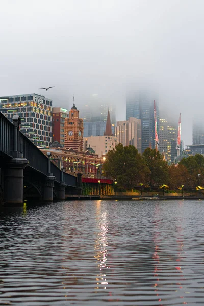 MELBOURNE, AUSTRALYA - 14 Nisan 2019: Melbourne CBD 'yi kaplayan sis ile soğuk bir sabah Flinders Caddesi İstasyonu.