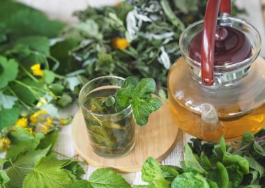 Ahşap bir arka planda tıbbi bitkiler. Bitki çayı ve kurutmak için kullanışlı bitkilerle birlikte çaydanlık. Gelecek için şifalı bitkilerin bahar hazırlıkları.