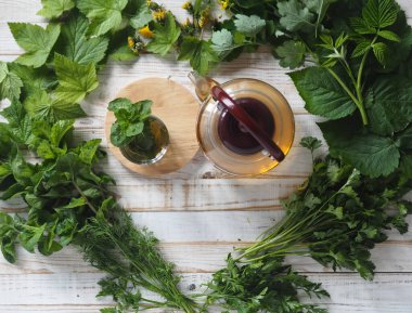 Kurutmak için hazırlanmış şifalı ot ve bitkilerle dolu bir kalp modelinin ortasında bir çaydanlık ile bitki çayı. Gelecek için şifalı ve kullanışlı bitkiler hazırlıyoruz..