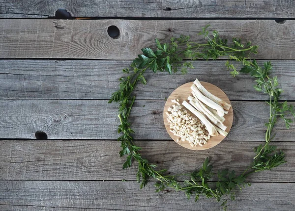 Medical and food background.Space for text. Spring harvesting of parsley root for use in medicine and nutrition.Parsley root on a wooden table in the center of a circle of leaves.