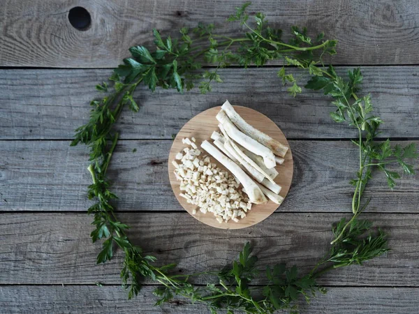 Medical and food background.Space for text. Spring harvesting of parsley root for use in medicine and nutrition.Parsley root on a wooden table in the center of a circle of leaves.