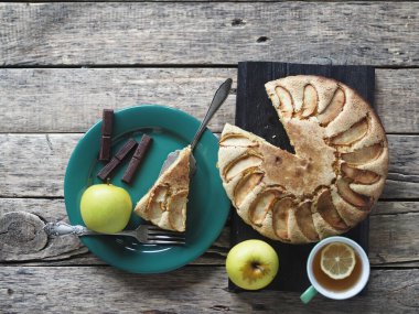 Kırsal ahşap arka planda yuvarlak ev yapımı elmalı turta. En tepeden manzara. Her bayram için elmalı ve çikolatalı hamur tatlısı..