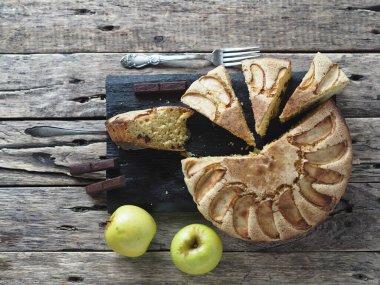 Kırsal ahşap arka planda yuvarlak ev yapımı elmalı turta. En tepeden manzara. Her bayram için elmalı ve çikolatalı hamur tatlısı..