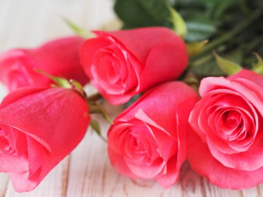 Önüne bak. Tatil için beyaz ahşap bir masada pembe güller. Tebrikler, mesaj için yer..