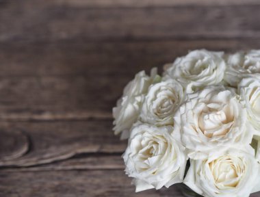 Tepeden manzara. Çiçek aranjmanı. Yoğun bir buket beyaz gül doğal bir ahşap masa üzerinde duruyor..