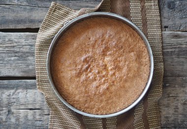 Ev yemeği. Muzlu bisküvi yapma süreci. Pişirme kabında hazır bisküvi eski bir ahşap masada soğur. Şekerleme arkaplanı.