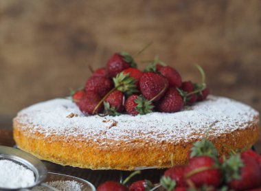 Ev yemeği. Üstünde muz ve çilek olan bir bisküvi yapma süreci. Hazır, krema şekeri serpiştirilmiş, ahşap zemin üzerine çilek serpiştirilmiş bisküvi. Şekerleme arkaplanı.