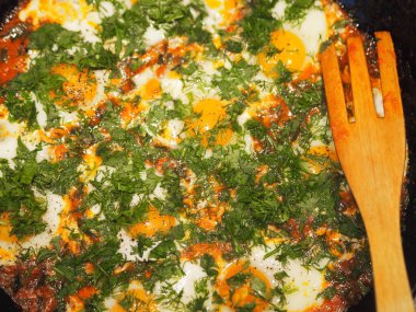 Yakın plan. Domates ve otlarla dolu tavada kızarmış yumurta resmi olan yemek arkaplanı. Sağlıklı yaz doğal gıdaları.