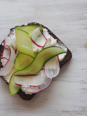 Yukarıdan bak. Arkaplanı aydınlat. Doğal ürünlerden, salatalıklardan ve turplardan yapılmış vejetaryen sandviçler. Sağlıklı doğal yaz yemekleri..