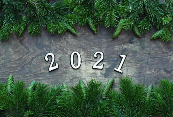 Happy New Year 2021. Branches of a Christmas tree are laid out on a wooden background. New year background with numbers 2021. — Stock Photo, Image
