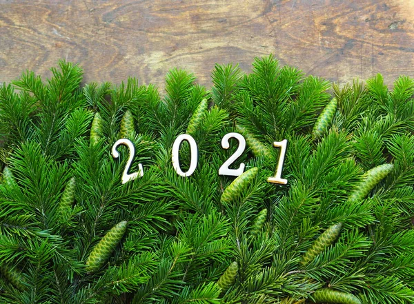 Happy New Year 2021. Branches of a Christmas tree are laid out on a wooden background. New year background with numbers 2021. — Stock Photo, Image