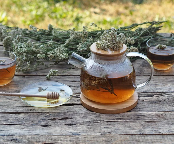 Herbal medicinal background.Healthy tea with yarrow flowers in a teapot with cups and honey on a wooden rustic background.