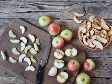 Kurutulmuş meyve toplama mevsimi. Elma cipsi, kurutulmuş meyve, kurutulmuş elma dilimleri, ahşap zeminde taze elmalar.
