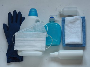 Tıbbi maskeler, mavi koruyucu eldivenler, beyaz arka planda ıslak mendil ve deterjan. Kendini virüsten korumak için bahar temizliği yap..