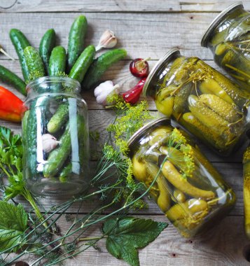 Kışın depolamak için cam kavanozların altındaki salatalıkları konserveleme işlemi. Ahşap arka planda muhafaza için gerekli malzemelerle dolu kavanozlar dolusu salatalık. Konserve salatalığın faydaları ve zararları..