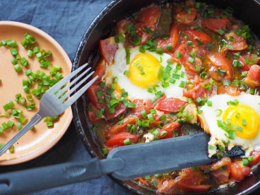 Yaz yemeği. Tavada domatesli yumurta ve otlar. Besleyici bir kahvaltı veya akşam yemeği..
