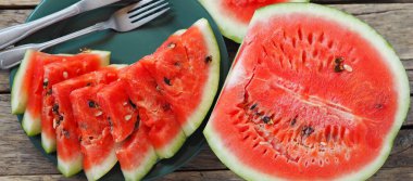 Ahşap bir masada yeşil bir tabakta kırmızı karpuz kes. Gıda arkaplanı.