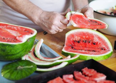 Karpuz Fruit Chips. Yaşlı bir kadının elleri kurutmak için karpuz dilimledi. Kurutucudan sebze ve meyve için siyah ızgara..