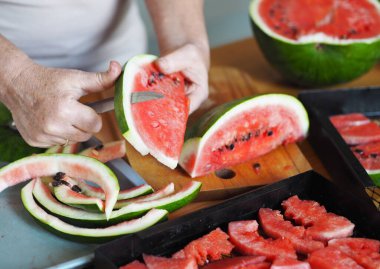Karpuz Fruit Chips. Yaşlı bir kadının elleri kurutmak için karpuz dilimledi. Kurutucudan sebze ve meyve için siyah ızgara..