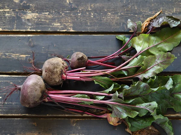 Beet with tops on a black wooden background