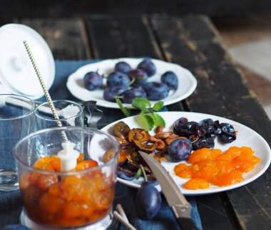 Meyve suyu ya da meyve suyu üretme aşamasındayız. Esmer arka planda erik ve malzemelerle karıştırılmış..