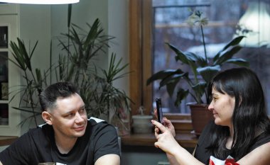 Şirin bir kız mütevazı bir adamın fotoğrafını çekiyor. Mutfakta ev partisi var..