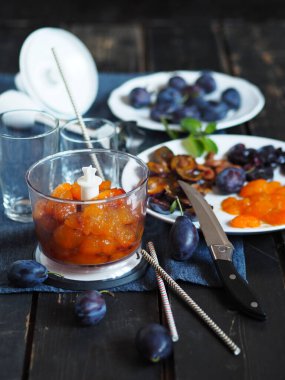 Meyve suyu ya da meyve suyu üretme aşamasındayız. Esmer arka planda erik ve malzemelerle karıştırılmış..