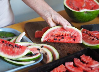 Yaşlı bir kadının elleri kuruması için bir karpuzu dilimlere ayırdı. Sonbahar meyveleri ve meyveleri. Tarım geçmişi ve karpuzlar. Kurutulmuş meyve toplama mevsimi.