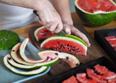Karpuz Fruit Chips. Yaşlı bir kadının elleri kurutmak için karpuz dilimledi. Kurutucudan sebze ve meyve için siyah ızgara..