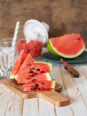 Mutfaktaki masada bir bardak taze karpuz suyu. Olgun karpuzlar ve arka planda dilimler. Vitamin bakımından zengin sağlıklı eko tatlı yiyecekler. Organik tarımın popüler ürünü.