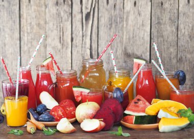 Bir yığın taze meyve ve ahşap bir masada farklı renklerde taze hazırlanmış kokteyller. Kırsal biçim.