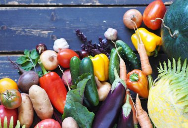 Kırsalda yetişen çeşitli doğal sebzeler ve meyveler, koyu ahşap bir arka planda. Sonbahar hasadı. Boş kopyalama alanı.