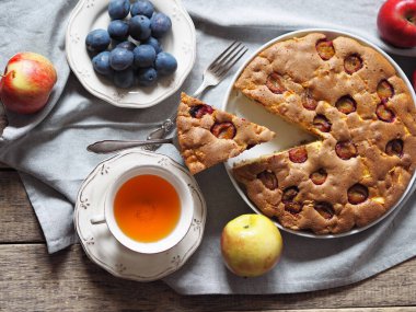 Elma ve erikli yeni pişmiş yaz turtasıyla birlikte beyaz bir seramik teneke kutuya konmuş kek ve malzemeler beyaz bir ahşap masa üzerinde. Gıda arkaplanı.