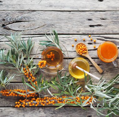 Böğürtlen, çay, bal ve ahşap zemin üzerinde deniz dikenli karabatak dalları. Tedavi amaçlı deniz dikenli gübre hasat mevsimi..