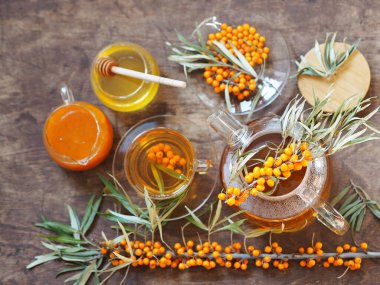 Çaydanlık, çay, deniz dikenleri, bal ve reçel ahşap bir masada. Deniz dikenli çay ile tıbbi geçmiş.