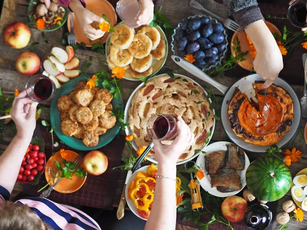 Concepto de celebración del Día de Acción de Gracias. La gente toma alimentos naturales caseros saludables con sus manos. Los huéspedes son manos sobre la mesa con comida. Mucha comida.. —  Fotos de Stock