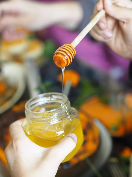 Día de Acción de Gracias. Miel natural líquida que fluye de un pincho sobre el fondo de una mesa servida. Alimento saludable. — Foto de Stock