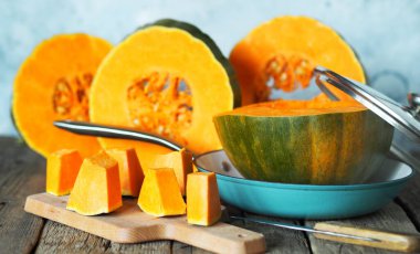 Gri bir arka planda, kızarmış tavada dilimlenmiş portakal kabağı..