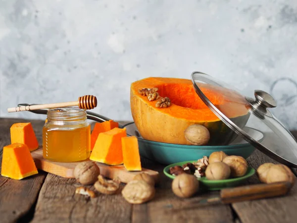 Pomerančová dýně nakrájená na plátky v pánvi s medem a vlašskými ořechy na šedém pozadí. Domácí vaření.Podzimní pozadí. — Stock fotografie