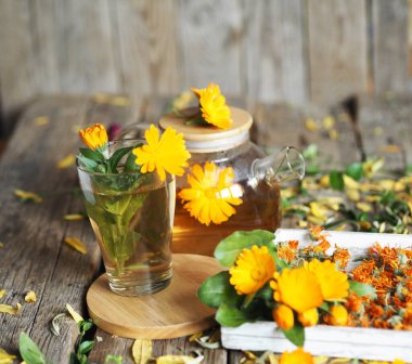 Tedavi amaçlı sonbahar arkaplanı. Çaydanlık, kurumuş ve taze çiçekli bitkisel sağlıklı kadife çayı..