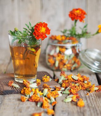 Sonbahar tıbbi geçmişi. Kadife çiçekli bir bardak bitki çayı. Ahşap arka planda. Kadife çayı sağlığına iyi gelir..