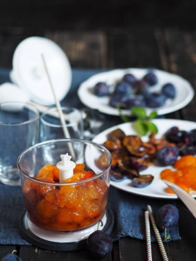 Meyve suyu ya da meyve suyu üretme aşamasındayız. Esmer arka planda erik ve malzemelerle karıştırılmış..