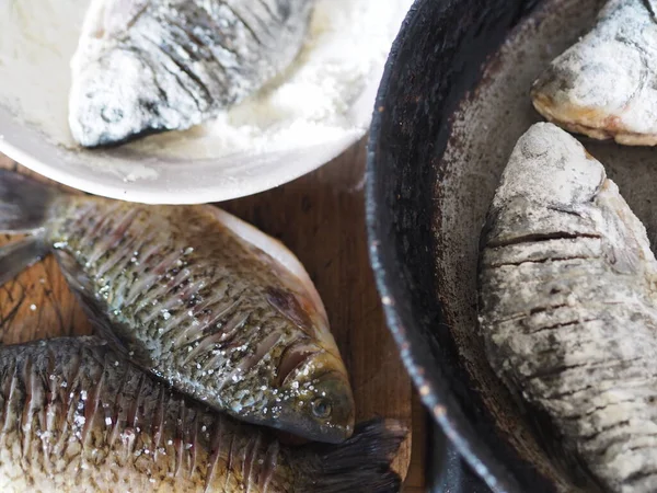 The process of frying river fish crucian carp in a pan on a kitchen stove. River fish of Russian rivers.