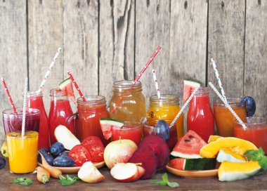 Bir yığın taze meyve ve ahşap bir masada farklı renklerde taze hazırlanmış kokteyller. Kırsal biçim.