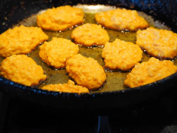 Diet pancakes made from natural pumpkin and millet are fried in a black pan.Home cooking, rustic style — Stock Image Diet Pancakes Made Natural Pumpkin Millet Fried Black Pan Home Stock Picture